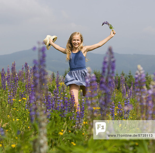 Austria  Teenage girl running in lupine field  smiling  portrait