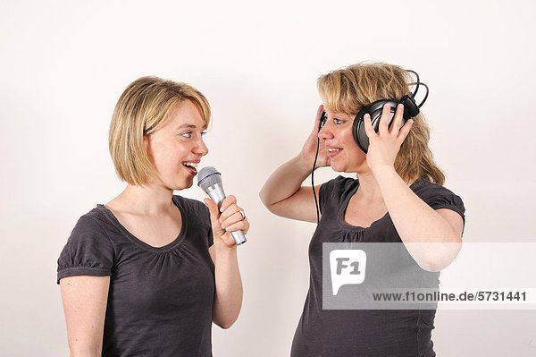Zwillingsschwestern mit Mikrofon und Kopfhörer
