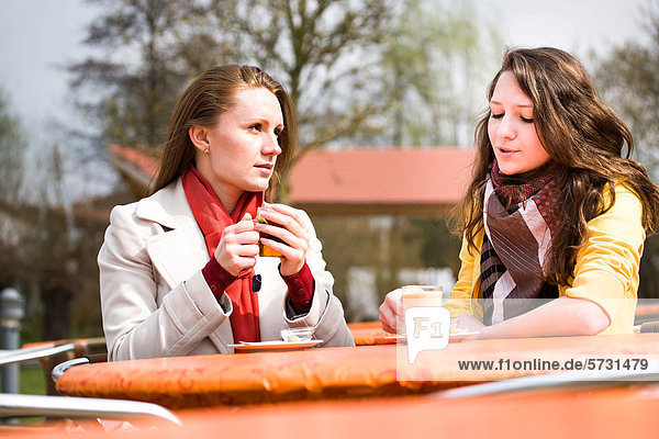 Junge Frau und Mädchen  Teenagerin sitzen in einem Straßencafe