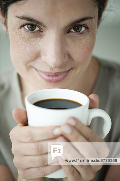 Erwachsene Frau hält eine Tasse Kaffee.