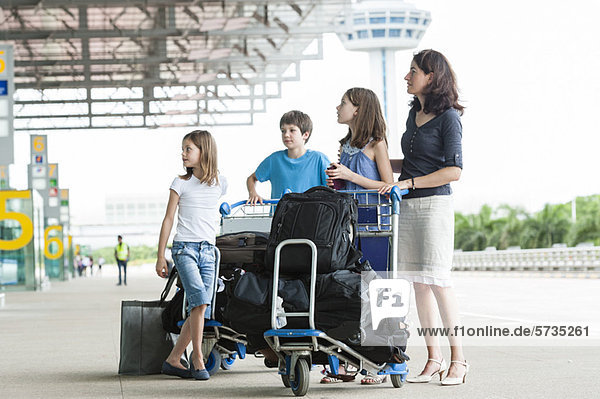 Familie steht vor dem Flughafen mit Gepäck