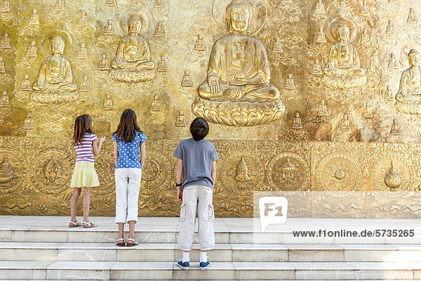 Junge Touristen schauen auf das buddhistische Flachrelief