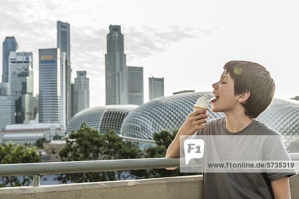 Junge beim Eis essen  Stadtsilhouette im Hintergrund