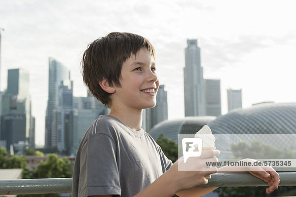 Junge mit Eistüte  Stadtsilhouette im Hintergrund