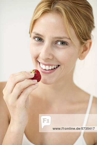Junge Frau isst Erdbeere  Portrait