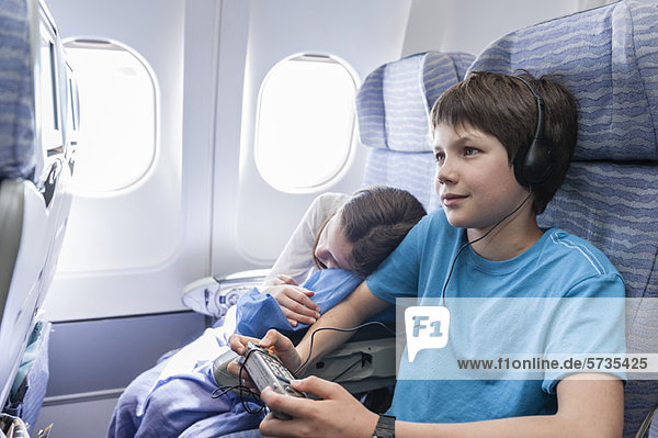 Junge mit Fernbedienung zum Kanalwechsel im Flugzeug