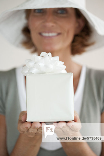 Frau hält verpacktes Geschenk bereit