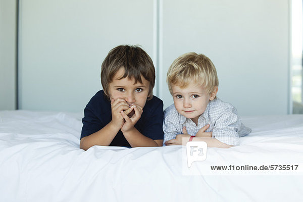 Young brothers lying on bed side by side  portrait