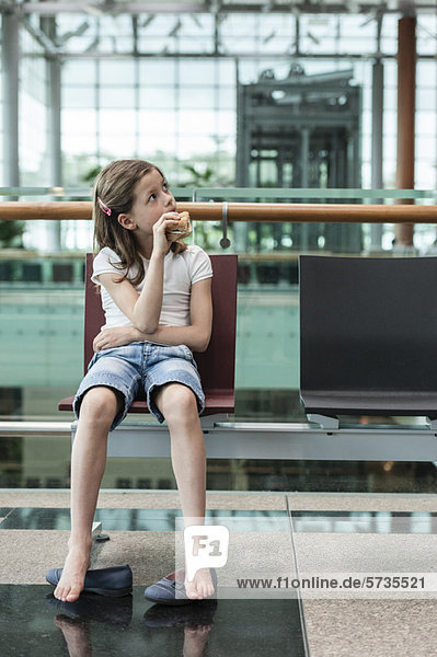Mädchen sitzt im Flughafen und isst Sandwich  Porträt