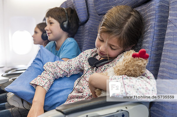 Mädchen schläft im Flugzeug mit Plüschtier