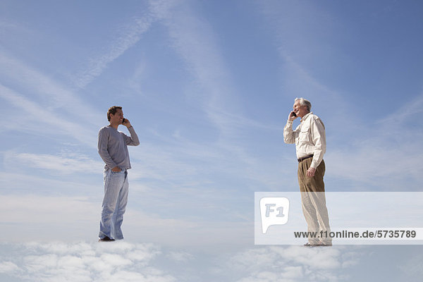 Männer  die auf Wolken stehen und Handys benutzen.