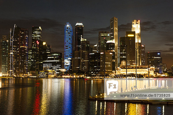 Singapur  Skyline am Wasser von der Promenade bei Nacht gesehen