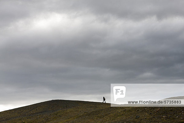 Island  Person  die auf einem kargen Hügel spazieren geht.