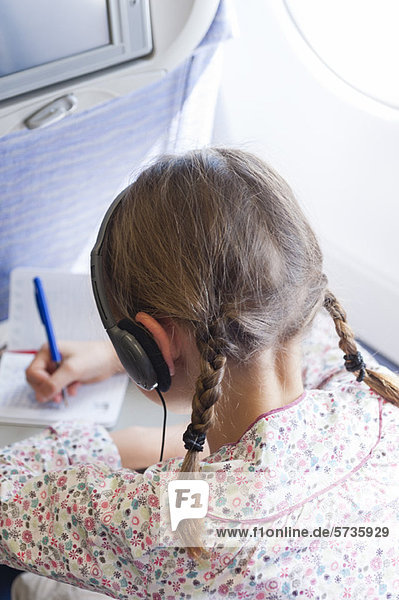 Mädchen beim Schreiben im Flugzeug