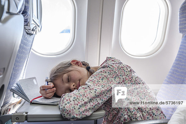 Mädchen ruhen Kopf auf Tablett-Tisch im Flugzeug