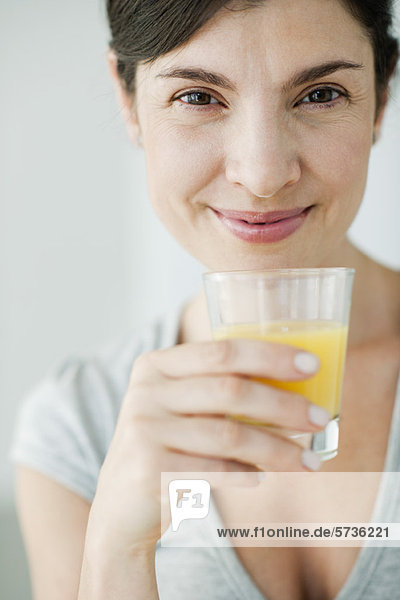 Frau im mittleren Erwachsenenalter mit einem Glas Orangensaft