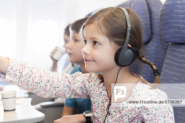 Mädchen sehen Film mit Kopfhörer im Flugzeug