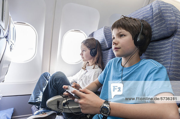 Junge mit Fernbedienung zum Kanalwechsel im Flugzeug