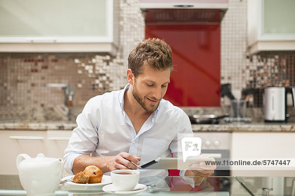 Smiling man reading at breakfast