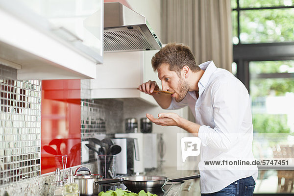 Man tasting food in kitchen