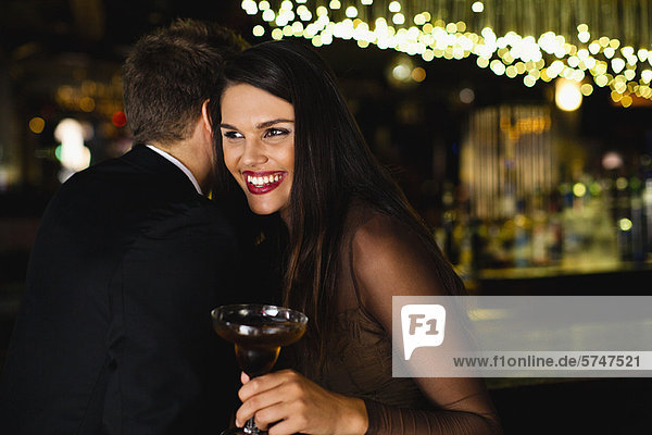 Smiling couple whispering at bar