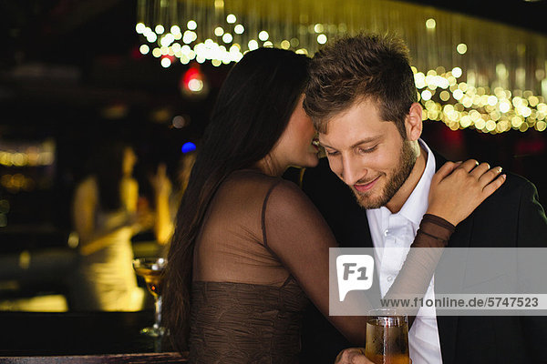 Lächelndes Paar flüstert an der Bar