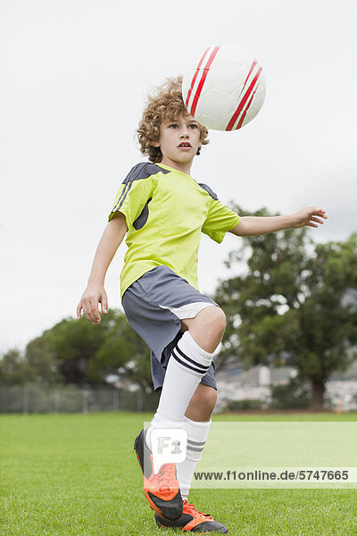 Junge spielt mit Fußball im Feld