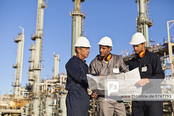 Arbeiter mit Blaupausen in der Ölraffinerie
