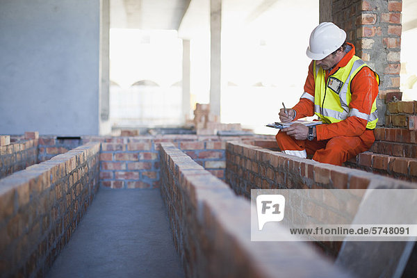 Worker writing on clipboard on site