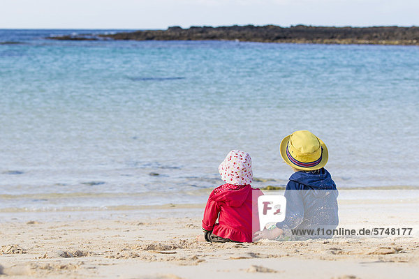 Children sitting on sandy beach