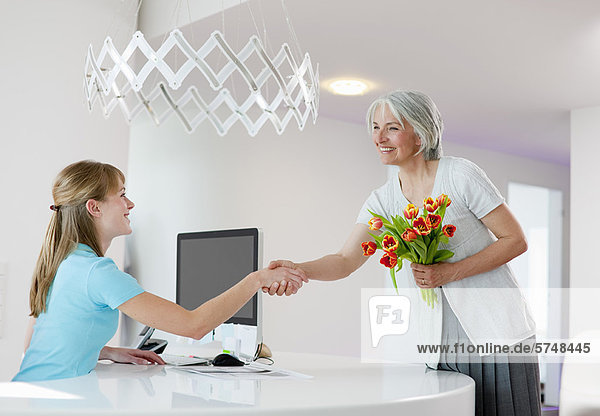 Receptionist shaking womans hand