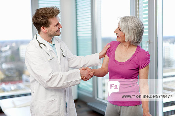 Arzt schüttelt Frauen Hand in Hand im Büro