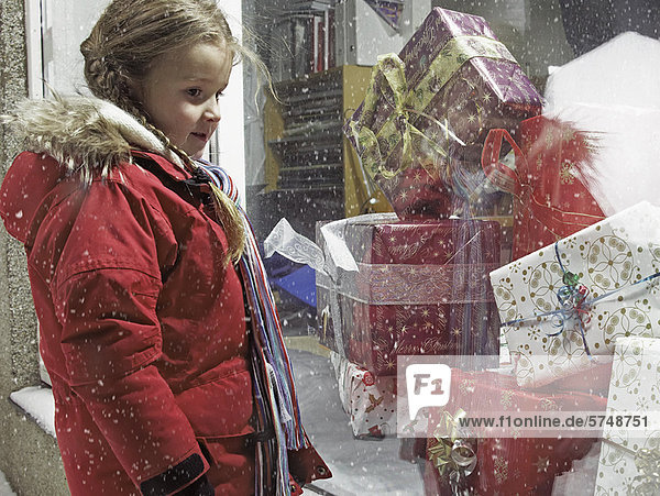Mädchen bewundert Weihnachtsgeschenke im Schnee