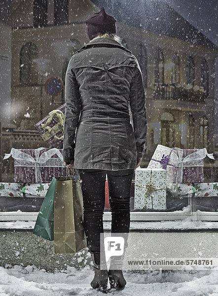 Frau trägt Einkaufstaschen im Schnee