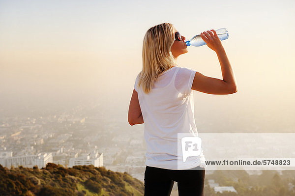 Woman drinking water on hilltop