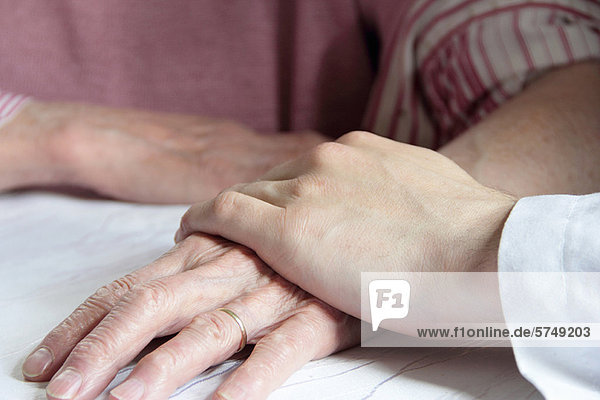Arzt hält ältere Frauenhand