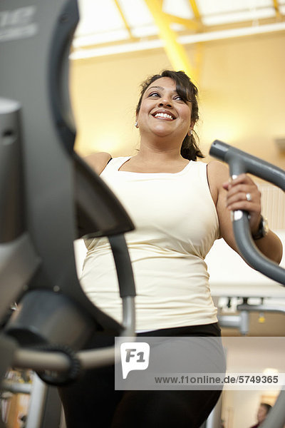 Woman using elliptical machine in gym
