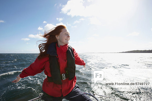 Young woman sailing with arms out