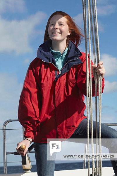 Young woman holding onto rope on yacht