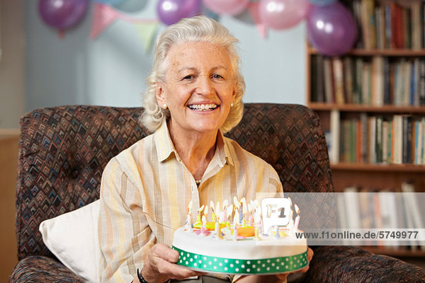 Seniorin mit Geburtstagskuchen  Portrait