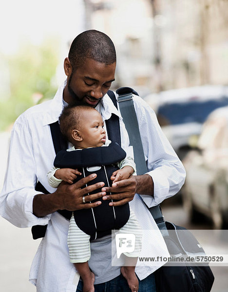 Mid adult man carrying son in baby sling