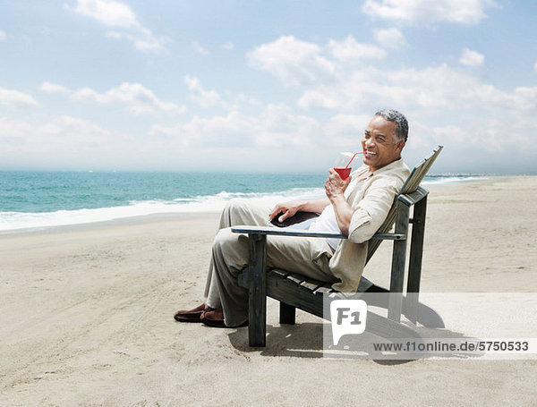 Mature man relaxing in chair on beach