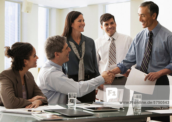 Businessman shaking hands in office with colleagues