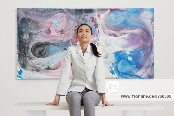 Junge Frau sitzt vor Öl-Malerei in der Galerie