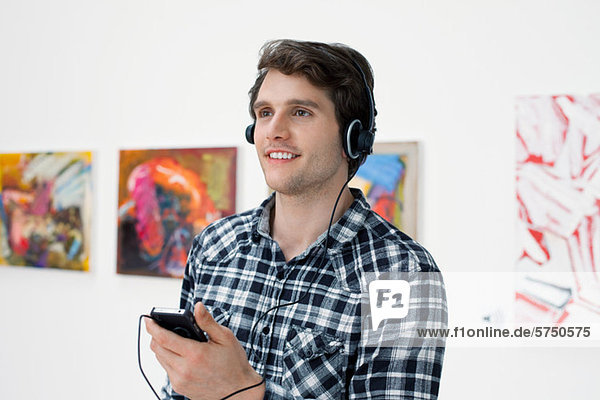 Young man using audio guide in art gallery