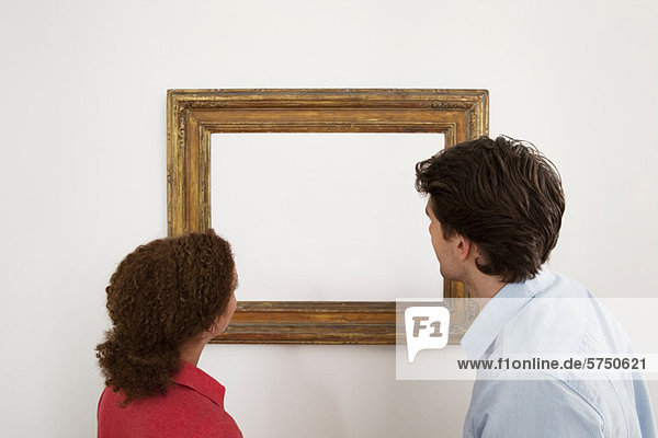 Junges Paar beim Betrachten eines leeren Bildes im Bilderrahmen