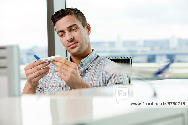 Young man looking at model aeroplane in office