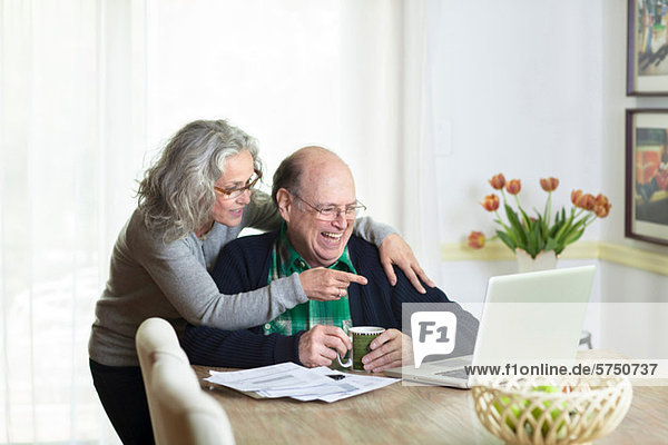 Senior Paar mit Laptop zu Hause,  lachend