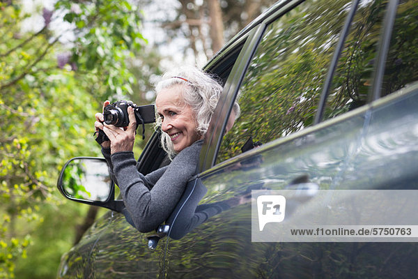 Senior woman photographing man car