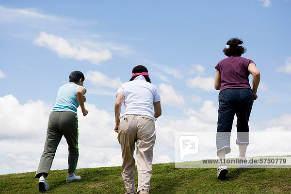 Drei ältere Frauen  die einen Hügel hinaufgehen.